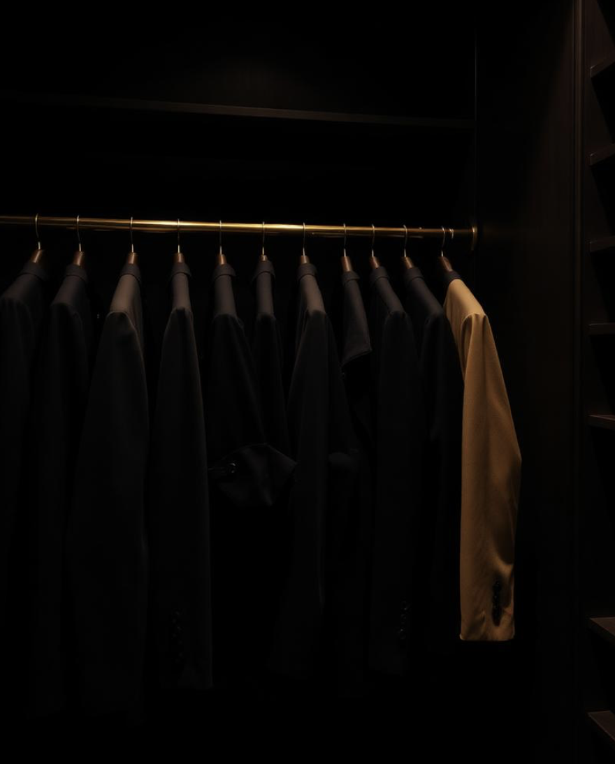 A rail of tailored coats in a dark dressing room